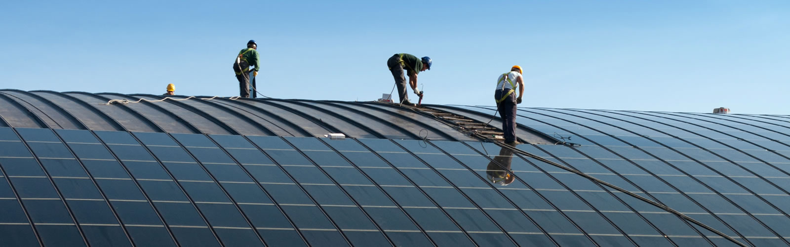 Photo of workers installing solar panels on a building rooftop.