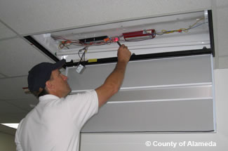 Photo of County employee replacing a lighting unit.
