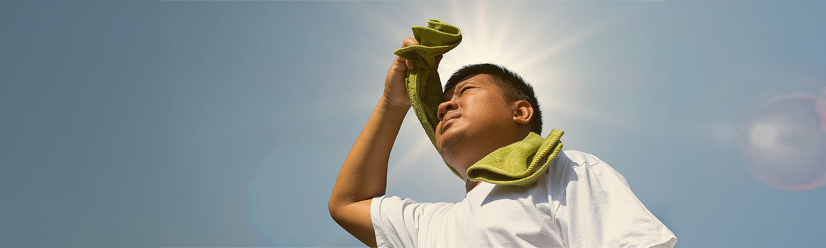 man with towel around his neck shielding eyes from sun