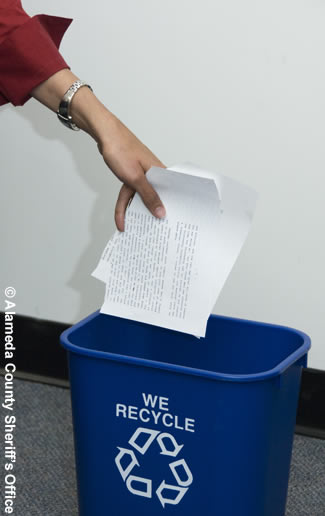 Photo of an employee putting papers in a recycle can.