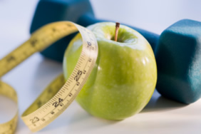 an apple, tape measure, and dumbbell weight